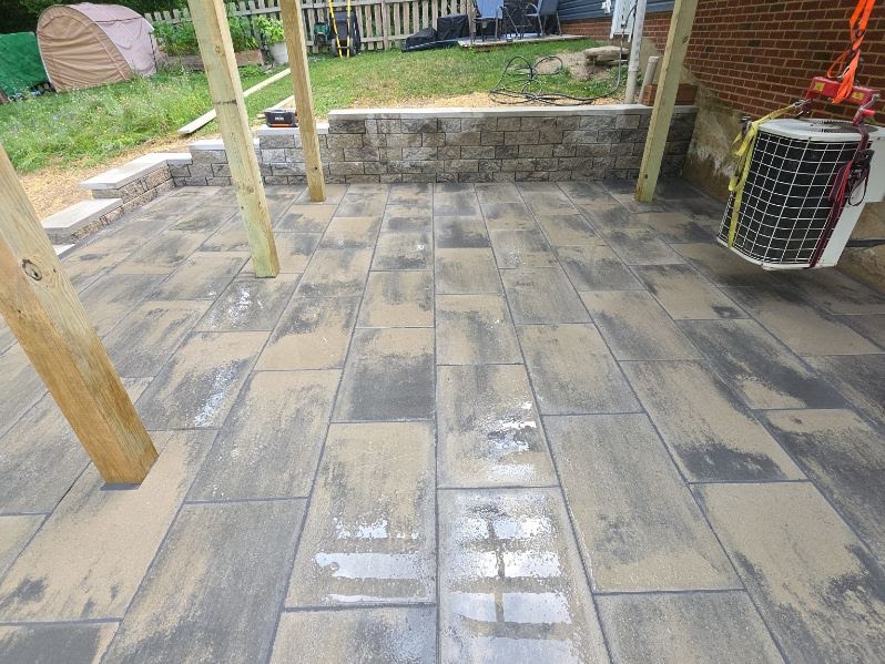 Wide view of a large-format paver patio bordered by a stone wall