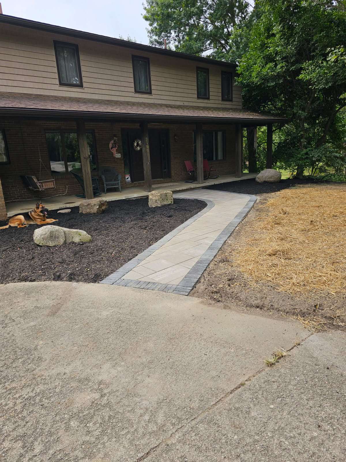 Curved paver walkway with charcoal border leading to a covered front porch
