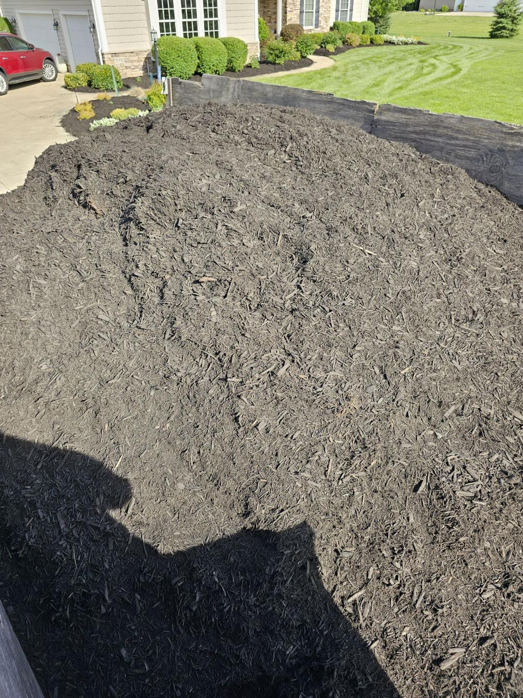 Freshly spread dark mulch bed along a timber retaining wall